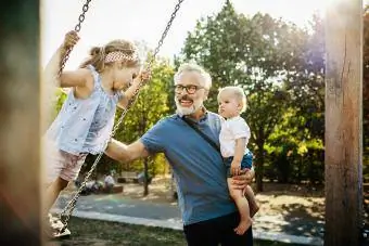 Nonno divertendosi con i nipoti sulle altalene