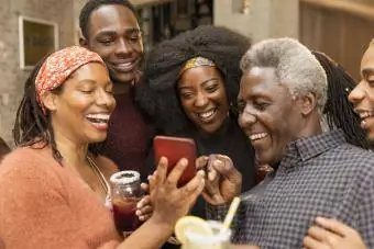 Keluarga berbilang generasi yang bahagia menggunakan telefon pintar