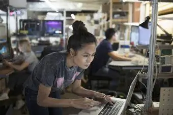 वर्कशॉप में लैपटॉप पर काम कर रही फोकस्ड महिला इंजीनियर