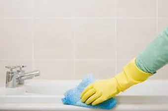 Femme nettoyant la baignoire avec des gants