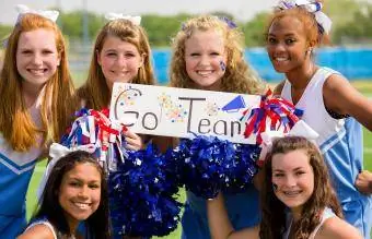 Gruppo di cheerleader con il cartello "go team".