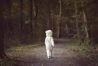 Klein kind draagt een wit beerpak in het bos