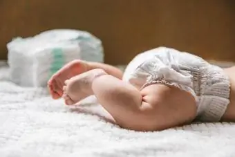 Een baby in een luier van twee maanden oud en een stapel luiers