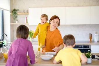 Moeder met drie kleine kinderen binnenshuis in de keuken in de ochtend thuis