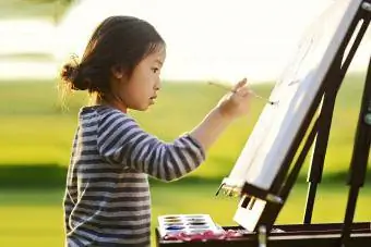 lapsi käyttää maalaustelinettä maalaamiseen