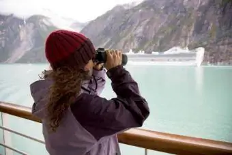 Žena používajúca ďalekohľad na aljašskej výletnej lodi