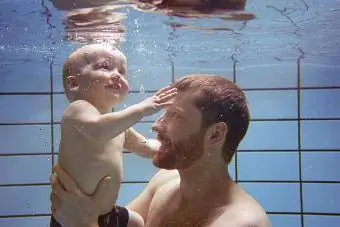 Far og sønn svømmer sammen under vann