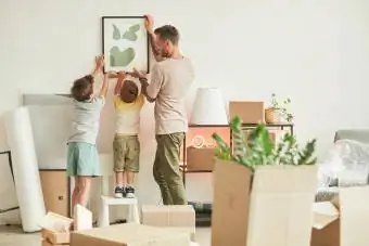 Heureux père avec deux fils accrochant des photos au mur lors de leur emménagement dans une nouvelle maison