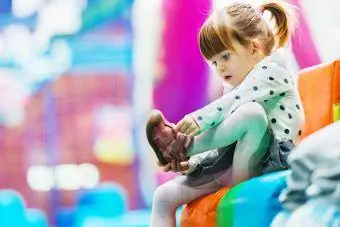 Niña quitándose los zapatos en la sala de juegos