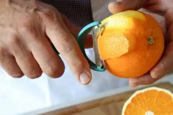 cáscara de naranja usando un pelador para decorar cócteles