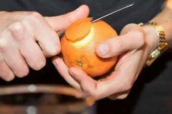 nhân viên pha chế bóc đồng xu cam quýt để trang trí cocktail