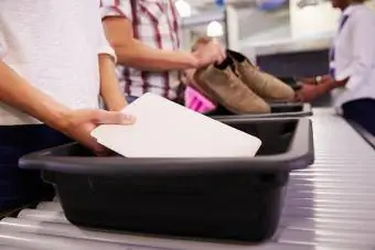 مرد تبلت دیجیتال را برای بررسی امنیت فرودگاه در سینی قرار می دهد