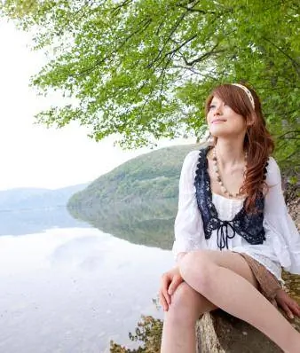 Nuori nainen istuu järven rannalla