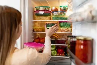 Kvinde tager madrester fra køleskabet