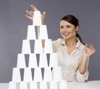 Noia construint piràmide de copes