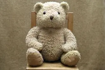 Vieil ours en peluche assis sur une chaise en bois