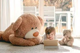 Niño viendo dibujos animados con dos ositos de peluche en casa