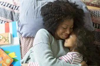 Mãe e filha sorridentes, abraçadas na cama