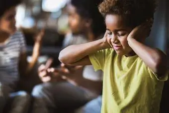 Niña tapándose los oídos mientras se niega a escuchar a sus padres discutir