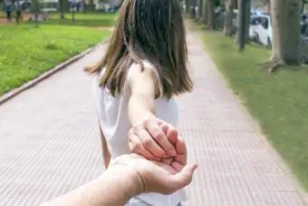 Achteraanzicht van een meisje dat de hand van haar vader vasthoudt