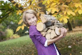Chlapec drží palivové drevo a usmieva sa