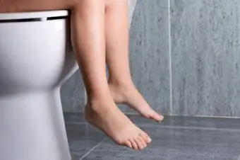 Naakte persoon wat op toilet sit