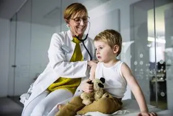 Doktor, yürümeye başlayan çocuğu stetoskopla muayene ediyor