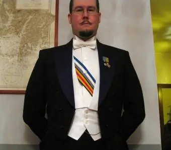 Moški, oblečen v smoking z belo kravato in okraski