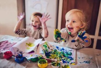 Fröhliche kleine Kinder, die Spaß beim Fingermalen haben