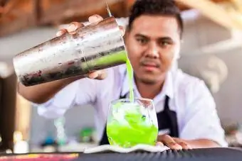 Barman masculin préparant un cocktail vert au bar