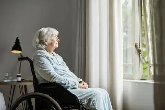 Zamišljena starija žena koja sjedi u invalidskim kolicima