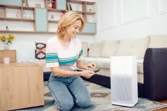 Kobieta dostosowująca domowy oczyszczacz powietrza
