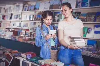 Remaja membeli buku dan mencari informasi di tablet bersama ibunya