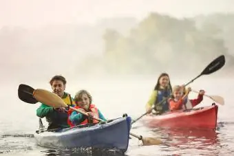 Ģimene bradā ar kanoe laivā ezerā