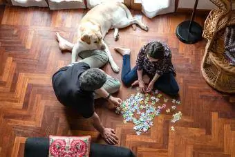 Pai e filha sentados no chão da sala, fazendo quebra-cabeças