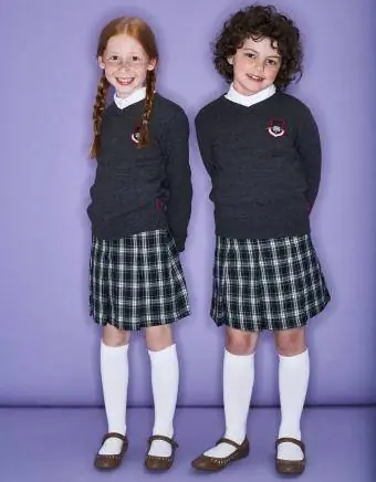 Dwie uśmiechnięte dziewczyny ubrane w mundurki szkolne