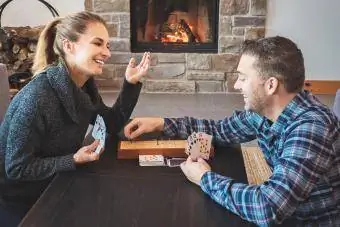 Pasangan bermain cribbage di rumah yang hangat dengan perapian