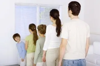 Keluarga berbaris paling pendek hingga paling tinggi, budak bongsu memandang ke atas bahu di seluruh keluarga