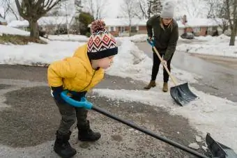 Sohn hilft Mutter beim Schneeschaufeln auf der Einfahrt