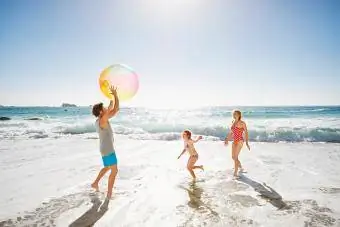 Familia jugando con pelota junto al océano