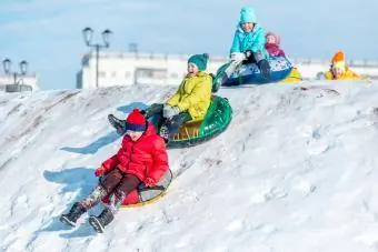 Gelukkige kinders teen die heuwel sneeubuise af