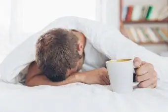 Mężczyzna z kacem próbujący obudzić się rano