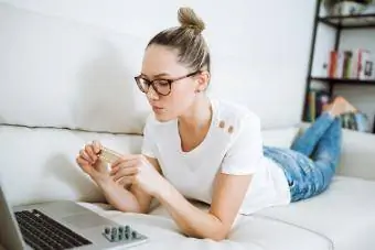 Donna che guarda la pillola contraccettiva mentre cerca informazioni online