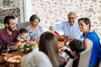 Home gran llatí servint el menjar a la seva família a la taula del sopar