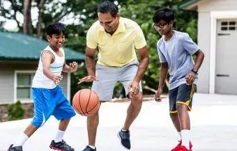 apa és két fia kosárlabdázik az otthon felhajtóján