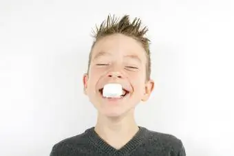 Junge hält Marshmallow zwischen den Zähnen