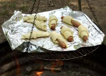 Battaniyeye sarılı domuzlar kamp ateşinde yemek pişiriyor