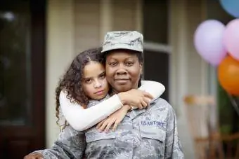 Fille embrassant sa mère soldat contre la maison