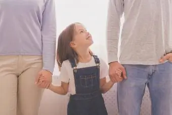 Niña feliz cogidos de la mano con sus padres