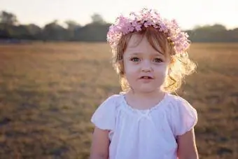 Jeune fille aux cheveux bouclés portant une couronne de fleurs dans la lumière dorée du coucher du soleil